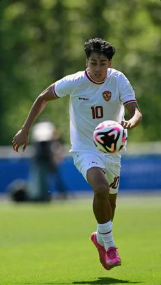 a young man kicking a soccer ball on top of a field