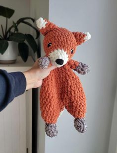 a person holding up a knitted stuffed animal