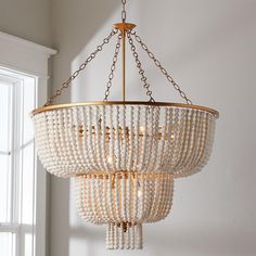 a chandelier with beads hanging from it's sides in front of a window