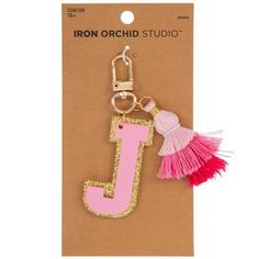 a pink and gold initial key chain with tassels