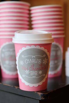 pink cups are lined up on a black table with red and white striped plates in the background