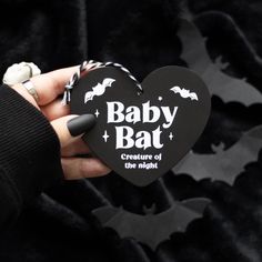 a hand holding a black heart shaped box with bats on it and the words baby bat creature of the night