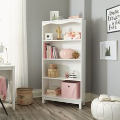 a white book shelf in a room with pink and white accessories on the top shelf