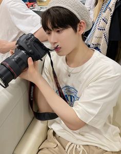 a young man sitting on a couch holding a camera