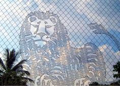 an image of a lion behind a mesh fence with palm trees in the foreground