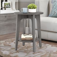 a small table with a book on it in front of a couch and coffee table