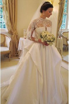 a woman in a white wedding gown standing next to a mirror