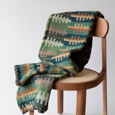 a chair with a blanket on top of it and a wooden arm rest in front of the chair