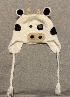 a knitted cow hat with black and white spots on the front, attached to a gray t - shirt