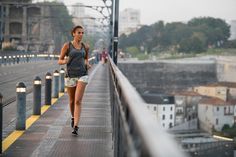 a woman running on a bridge with buildings in the background