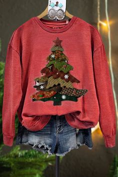 a red sweater with a christmas tree on the front is hanging from a clothes rack