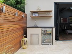 a small outdoor kitchen with an icebox and beverage dispenser on the counter