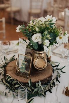 there is a table with flowers and cards on the wooden slice in front of it