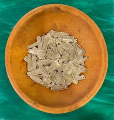 a wooden bowl filled with sea glass on top of a green tablecloth covered floor