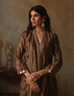 Silk tissue kurta adorned with resham, zari, and nakshi detailing in an asymmetrical design, complemented by resham, zari and tilla florals bootis on sleeves and back. Paired with zari weave pants,... Unstitched Luxury Gold Salwar Kameez, Luxury Tussar Silk Kurta With Embroidered Border, Luxury Salwar Kameez With Gold Embroidery And Straight Kurta, Luxury Art Silk Palazzo Set With Straight Kurta, Luxury Tussar Silk Kurta With Gota Work, Luxury Tussar Silk Kurta With Dori Work, Luxury Tussar Silk Unstitched Straight Kurta Suit, Luxury Unstitched Gold Salwar Kameez, Luxury Chanderi Traditional Wear With Gold Embroidery