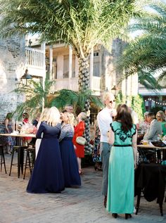 a group of people standing around each other in front of a building with palm trees