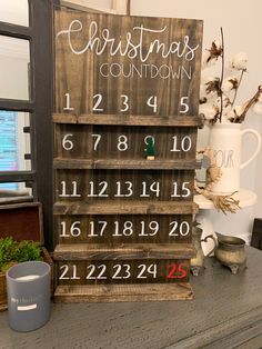 a wooden christmas calendar sitting on top of a table next to a cup and vase