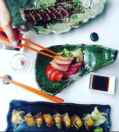 two plates with sushi and chopsticks next to each other on a table