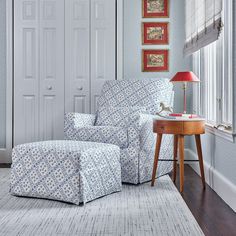 a chair and ottoman in a room with white walls, wood floors and blue patterned upholstered furniture