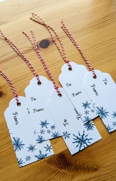 four tags with red and white twine on them sitting on a table next to candy canes