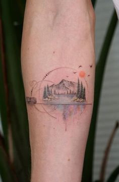 a person with a small tattoo on their leg that has trees and mountains in the background