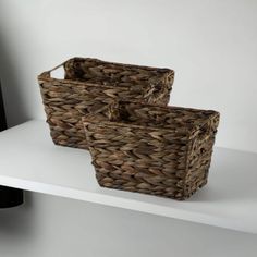 two baskets sitting on top of a white shelf