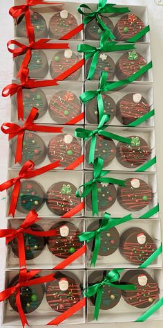 twelve chocolate covered cupcakes with red and green ribbons tied around them in boxes