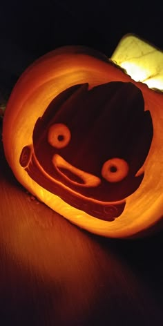 a pumpkin carved to look like a cat with eyes and nose, sitting on a table