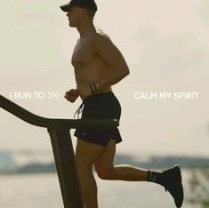 a shirtless man running down a metal rail near the ocean with words that read i run to calm my spirit