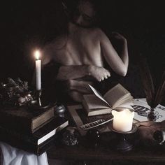 a person sitting at a table with books and candles in front of them on top of a desk