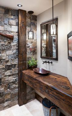 a rustic bathroom with stone walls and wood countertop, along with a vessel sink