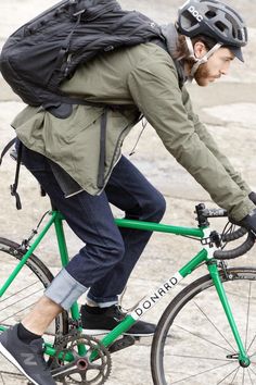 a man riding a green bike with a backpack on the back and his helmet down