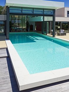 an empty swimming pool in front of a modern house