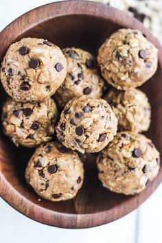 a wooden bowl filled with oatmeal chocolate chip energy bites on top of a white table