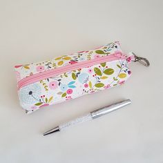 a pen and pencil case sitting next to each other on a white surface with a flower pattern