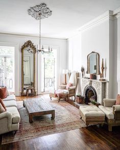 a living room filled with furniture and a fire place in front of a mirror on the wall