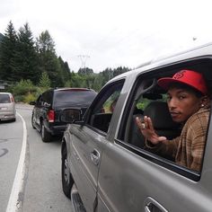 a man in a red hat sitting in the passenger seat of a silver pickup truck