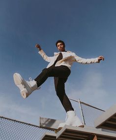 a man in white shirt and black pants doing a trick on a skateboard outside