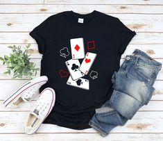 a t - shirt with playing cards on it next to some jeans and an old pair of shoes