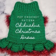 a green crochet christmas dress with red pom - poms on it