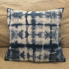 a blue and white pillow sitting on top of a couch