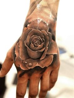 a person's hand with a rose tattoo on it