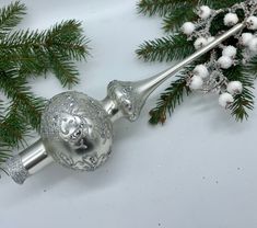 a silver christmas ornament sitting on top of a tree