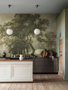 a kitchen with an island in front of a painting on the wall and wooden floors