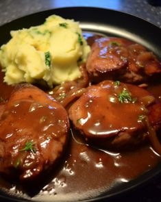 some meat and gravy on a plate with mashed potatoes