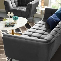 a living room with two gray couches and a white coffee table in front of a window