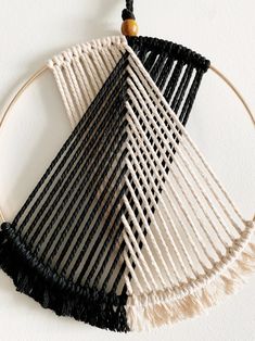 a black and white wall hanging with tassels on the end, in front of a white wall