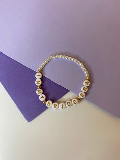 a beaded bracelet with the word love written on it, sitting next to a purple card