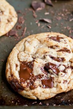 two chocolate chip cookies sitting on top of a cookie sheet