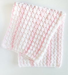 two pink and white crocheted dishcloths sitting on top of each other